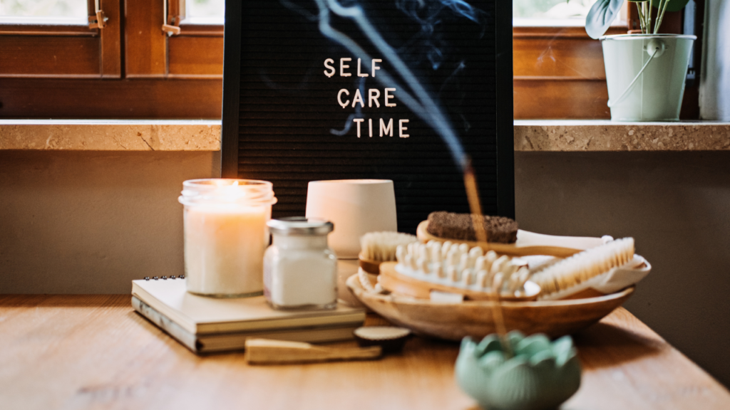 altar de autocuidado em tons terrosos e verde com escovas, velas, incensos e uma placa escrito self care time
